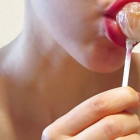 Sie hat knallrot geschminkte Lippen und lutscht verführerisch an einem Lollipop